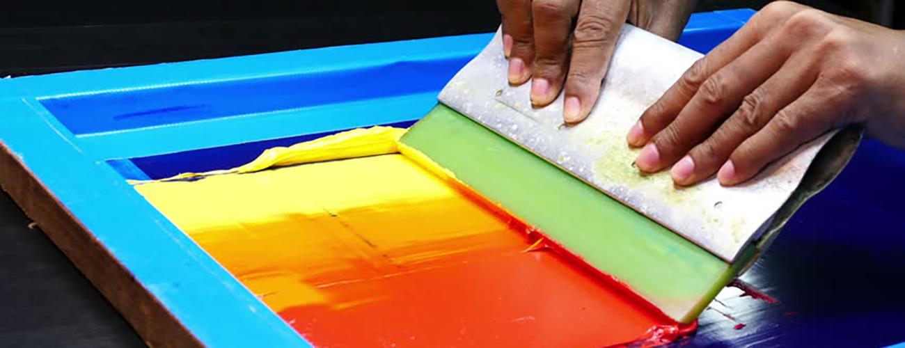 iemand gebruikt een spons om een ​​regenboogkleurige tafel te beschilderen
