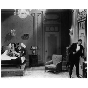 een man en vrouw staan ​​in een slaapkamer naast een bed