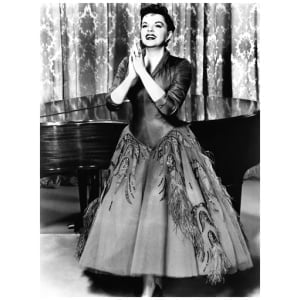 een vrouw in een jurk die naast een piano staat