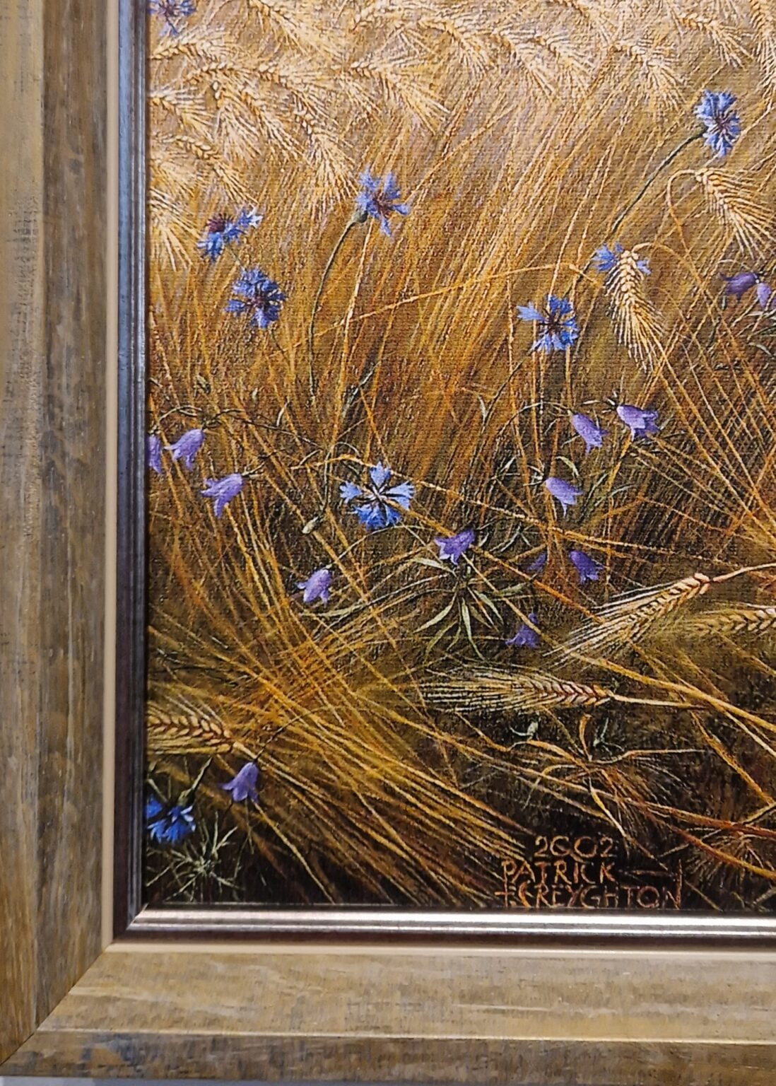 een schilderij van blauwe bloemen en gras in een lijst